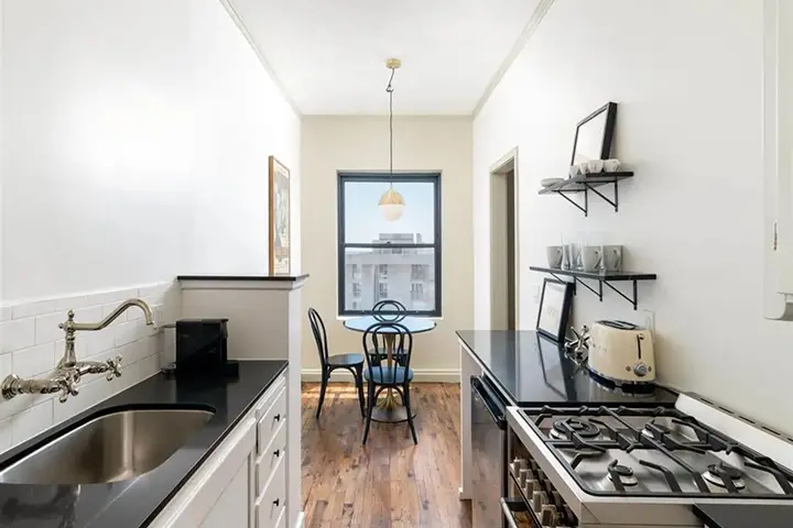 Bright kitchen with black countertops, stainless appliances, and round dining table.