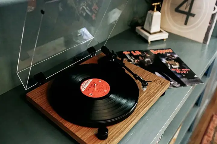 Vinyl record playing on wooden turntable with visible album cover.