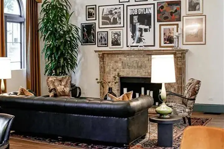 Living room with black leather sofa, cushions, fireplace, and indoor plant.